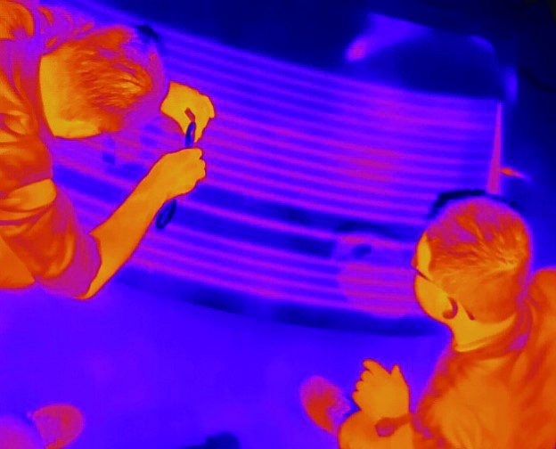 Operator handling an automotive glass panel viewed in thermal