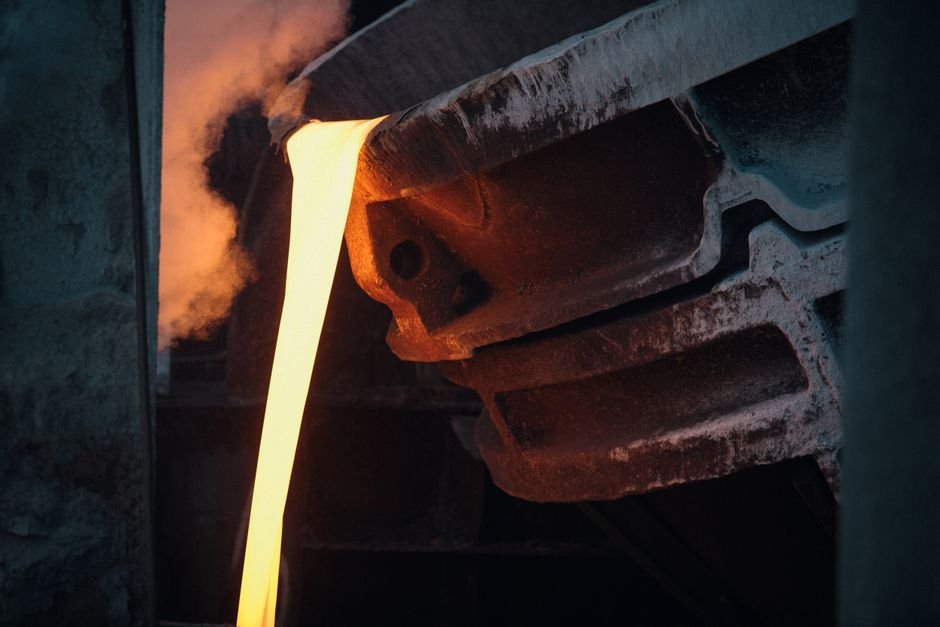 Molten steel being tapped in a steel plant, ladles in the background